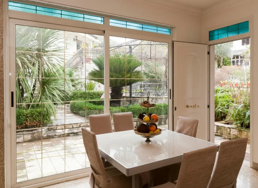 Apartmani Nautica Herceg Novi Trpezarija sa velikim staklenim vratima i pogledom na vrt u Apartmanima Nautica Herceg Novi