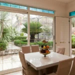 Trpezarija sa velikim staklenim vratima i pogledom na vrt u Apartmanima Nautica Herceg Novi